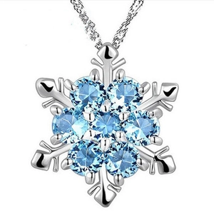 Collier pendentif flocon de neige argenté avec cristaux bleus sur fond blanc