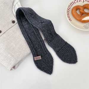 Close-up of dark grey knitted wool scarf featuring detailed rib-knit texture and 100% wool label