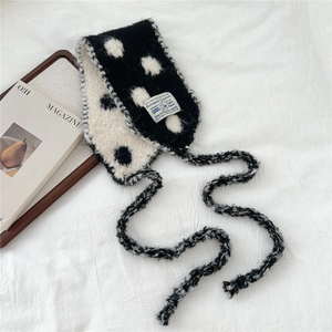 Detailed texture of black and white polka dot knit scarf with soft fabric and brand label