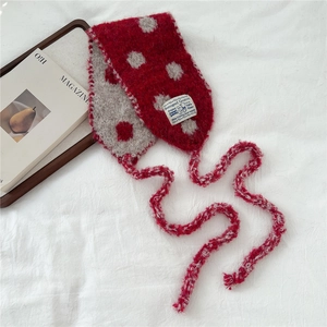 Close-up of red and beige polka dot knitted scarf with soft mohair texture and logo tag