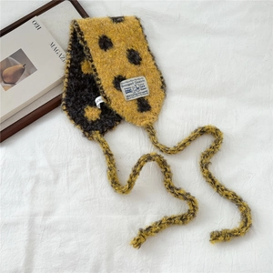 Detail of yellow knit scarf with black polka dots, mohair texture and branded label