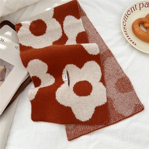 Detail of 100% wool knit scarf featuring bold floral patterns and a quality care label