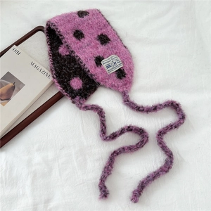Close-up of pink and black polka dot knitted scarf with soft wool texture and brand label