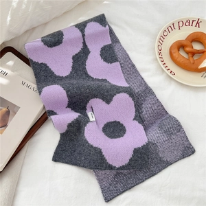 Detail of 100% wool knitted scarf featuring large purple floral pattern on dark grey