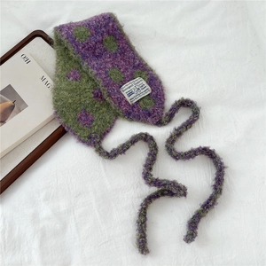 Detail of purple and green checkered knit hat with plush texture and woven logo label