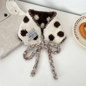 Detailed macro shot of polka dot knit scarf texture with a blue fabric label and tie