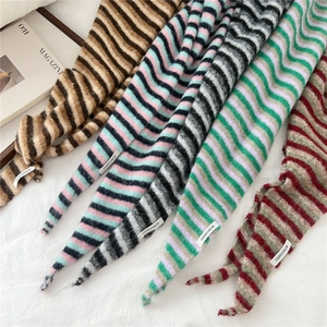 Close-up of fluffy striped knitted scarf with woven label and premium wool-like texture