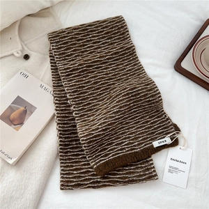 Detailed close-up of water ripple knit scarf featuring brown and white wavy texture