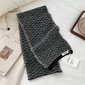 Detail of knit scarf with black and white wavy stripes and designer brand tag
