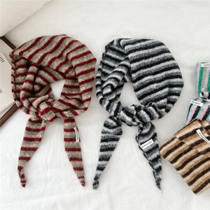 Knitted striped triangle scarves in multiple colors on a white textured background