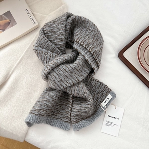 Close-up of gray and brown wavy striped knit scarf texture with brand label and tag
