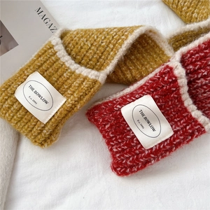 Detail of red and yellow knit scarves with contrast white piping and ribbed texture