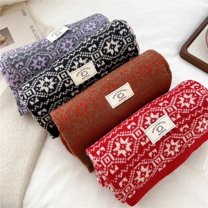 Detail of four Nordic knit wool scarves showing 100% wool label and snowflake patterns