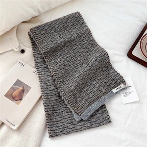 Close-up of gray and brown striped knit scarf with wave texture and logo label