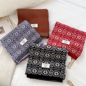 Flat lay of multiple wool knit scarves with snowflake patterns in red and gray colors