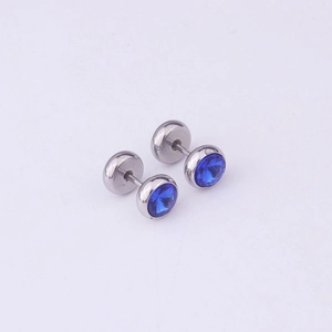 Macro shot of silver dumbbell earrings with sparkling round blue crystals on purple background