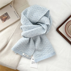 Close-up detail of soft blue and white striped knit scarf with branded woven label