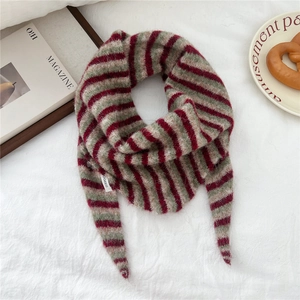 Detail of red, green, and grey striped knitted scarf with soft wool texture and label