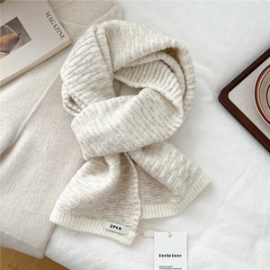 Macro detail of cream chunky knit scarf with ribbed texture and minimalist woven label