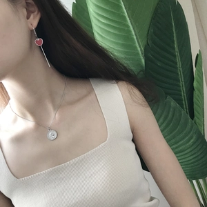 Macro detail of 925 silver coin pendant necklace and red heart earrings on model