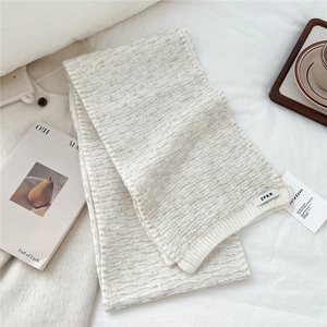 Macro shot of off-white knitted scarf showing detailed wavy texture and premium fabric finish