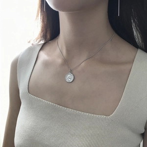 Close-up of 925 sterling silver vintage coin pendant necklace on a knitted garment