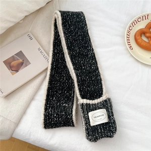 Detail shot of heavy-knit winter scarf with practical side pocket and branded label