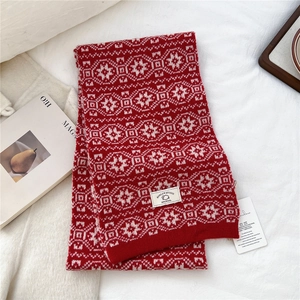 Close-up of 100% wool knit scarf featuring classic red and white Nordic snowflake patterns