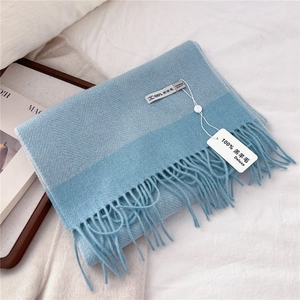 Close-up of light blue lambswool scarf featuring herringbone weave and fringe details