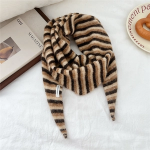 Detail of soft mohair striped scarf with brand label on a cozy white linen background