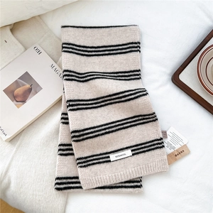 Detail of 100% wool label on beige and black striped knitted scarf with textured fabric