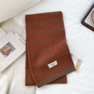 Macro detail of 100% wool knitted scarf showing retro geometric patterns and brand label