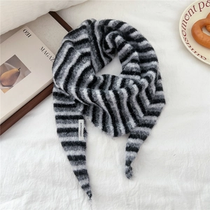 Detail of soft striped knit scarf with brand label on a cozy lifestyle background