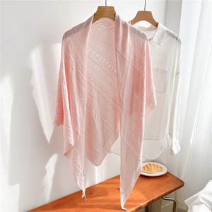Detail of light pink hollow knit shawl layered over a white shirt for a soft minimalist style