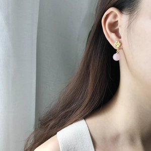 Close-up of a 925 silver flower stud earring with a pink pearl drop on a model's ear