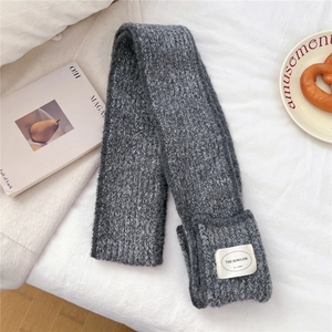 Close-up detail of dark grey knit scarf with soft texture and white brand label