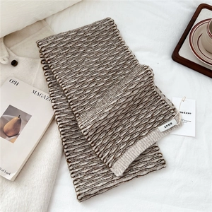 Detail of soft brown and beige wavy knit scarf with woven label on fabric background
