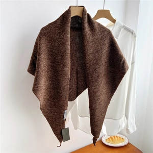 Detail of a brown wool-blend triangle scarf showing thick knit texture and tag