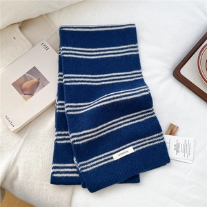 Close-up of 100% wool material tag on blue and white striped knitted winter scarf