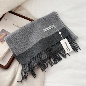 Close-up of gray chevron lambswool scarf texture showing tassel fringe and fabric label