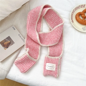 Detail of pink and beige knit scarf featuring a soft chunky texture and logo brand label