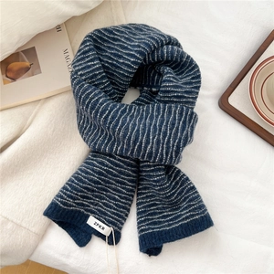 Detailed texture of navy blue and light gray striped knit scarf with a woven brand tag