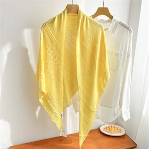 Detail of yellow knitted shawl with hollow diagonal stripes on a wooden clothes hanger
