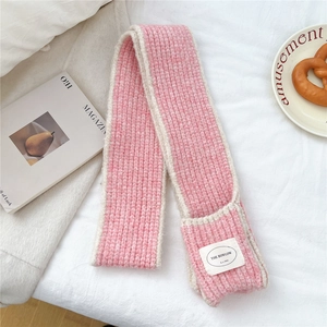 Close-up of pink and cream knitted scarf with a woven label on soft white bedding