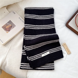 Detail view of striped wool scarf showing the knitted texture and 100% wool material label