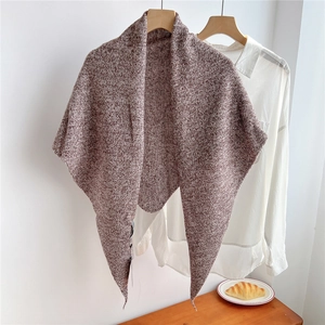 Detail of coffee and white knit wool triangle scarf texture hanging on wooden hanger