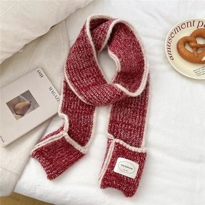 Detail of red and white knitted scarf with thick texture and branded woven label