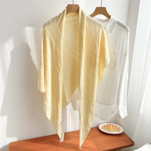 Detail of light yellow knit triangle shawl featuring hollow stripe patterns and soft texture