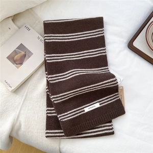 Close-up of a striped knit wool scarf with a 100% wool label in a lifestyle setting