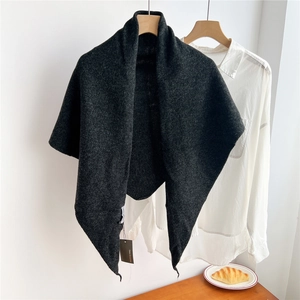 Macro shot of dark grey knit wool triangle shawl showing soft texture and wooden hanger detail
